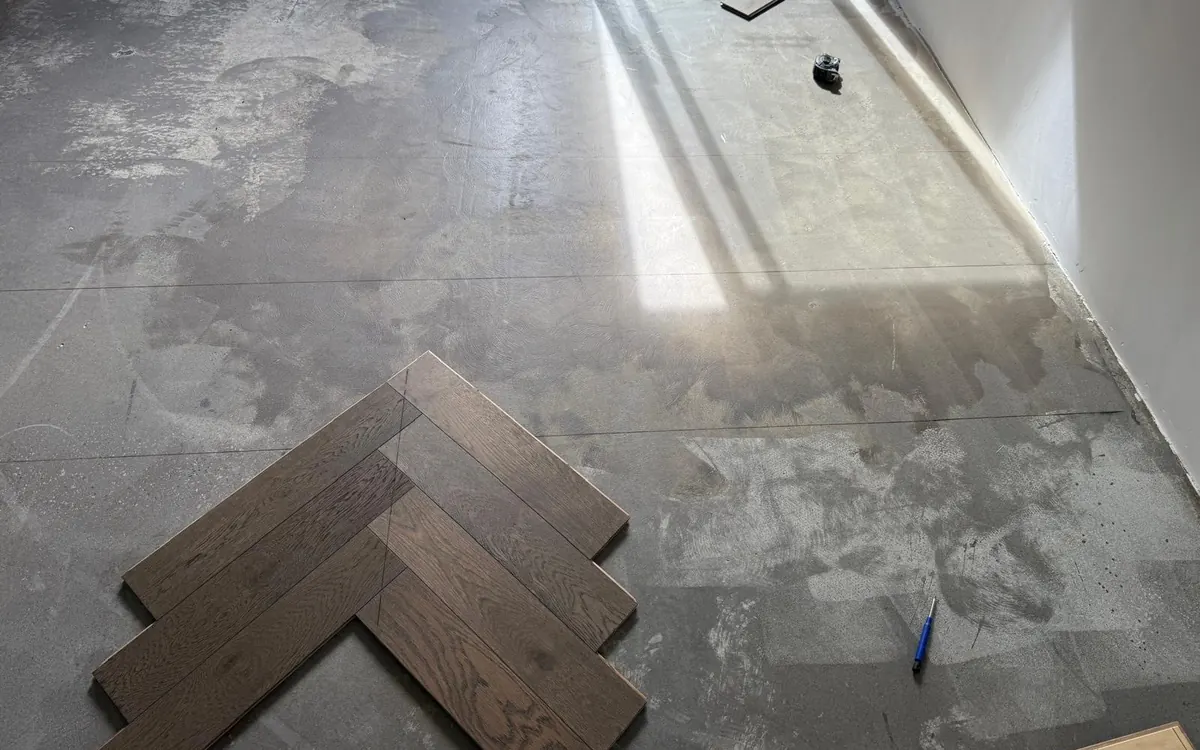 Living room before — bare subfloor with the first herringbone boards set out