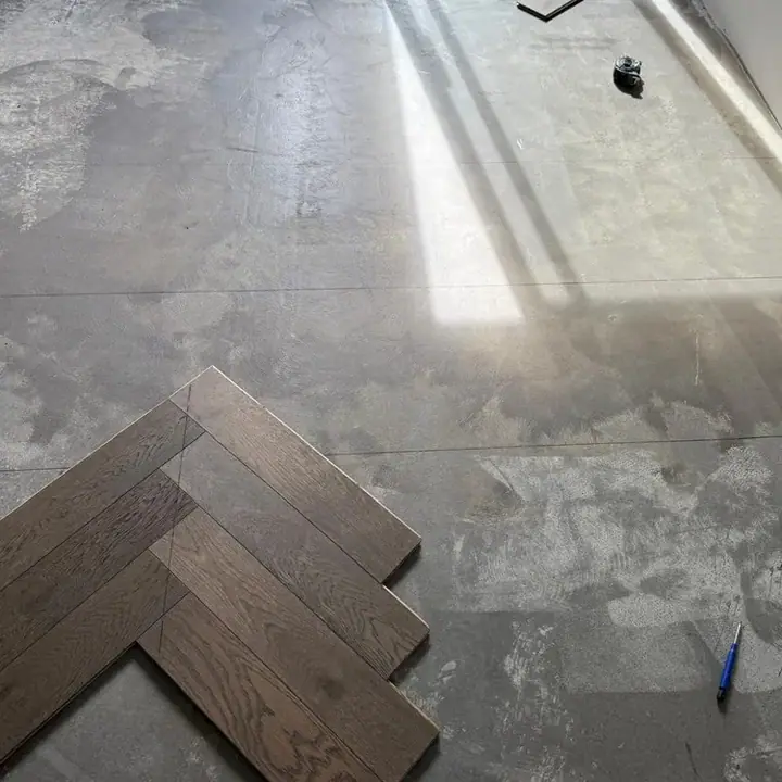 Living room before — bare subfloor with the first herringbone boards set out