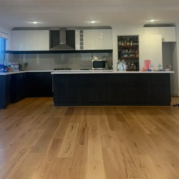 Open plan kitchen and living after — spotted gum flooring installed