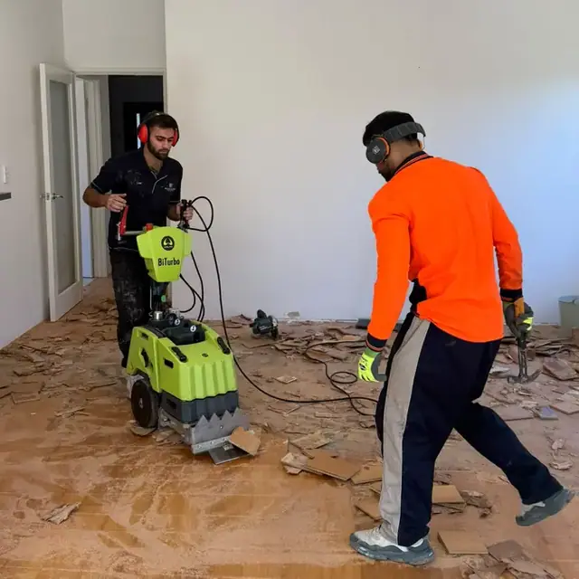 Two-man crew stripping an old floor back to the substrate