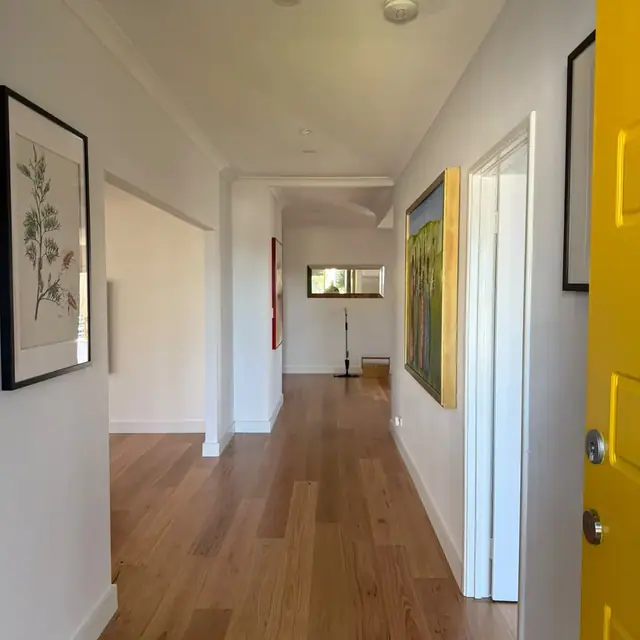 Engineered timber flooring running down a hallway to a yellow front door