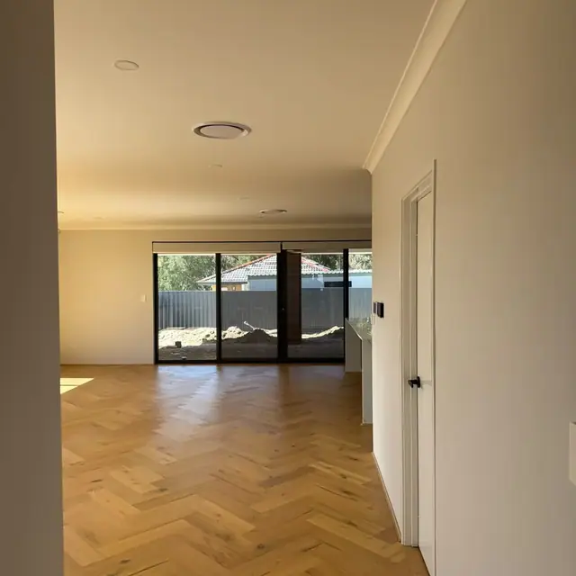 Herringbone flooring running through an open living area toward sliding doors
