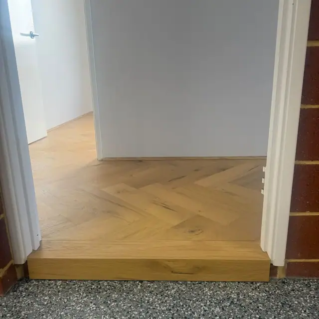 Herringbone flooring finished at a step-down threshold
