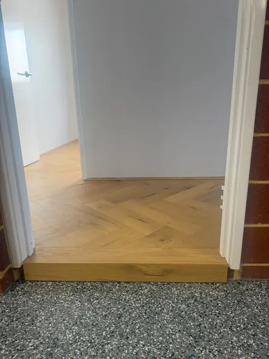 Herringbone flooring finished at a step-down threshold