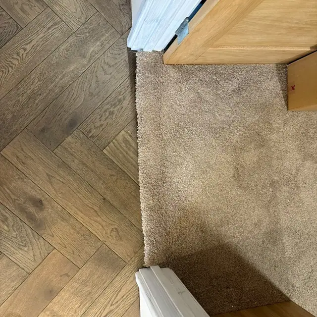 Herringbone flooring detailed where it meets the existing carpet