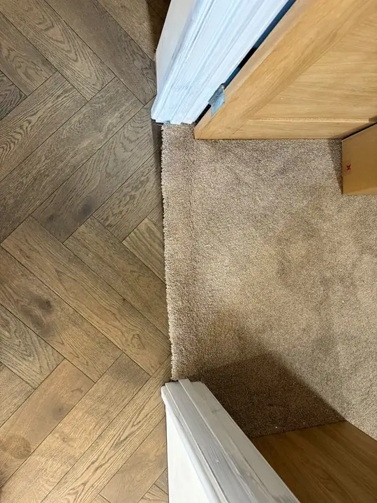 Herringbone flooring detailed where it meets the existing carpet