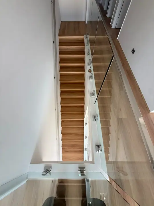 Timber stair treads with a glass balustrade, viewed from the landing